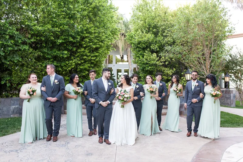 Full wedding party lined up on the courtyard, the women in mint green and the men in grey suits with mint ties