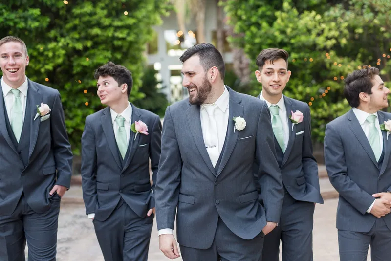 Groom walking the courtyard with his groomsmen in grey suits and mint ties