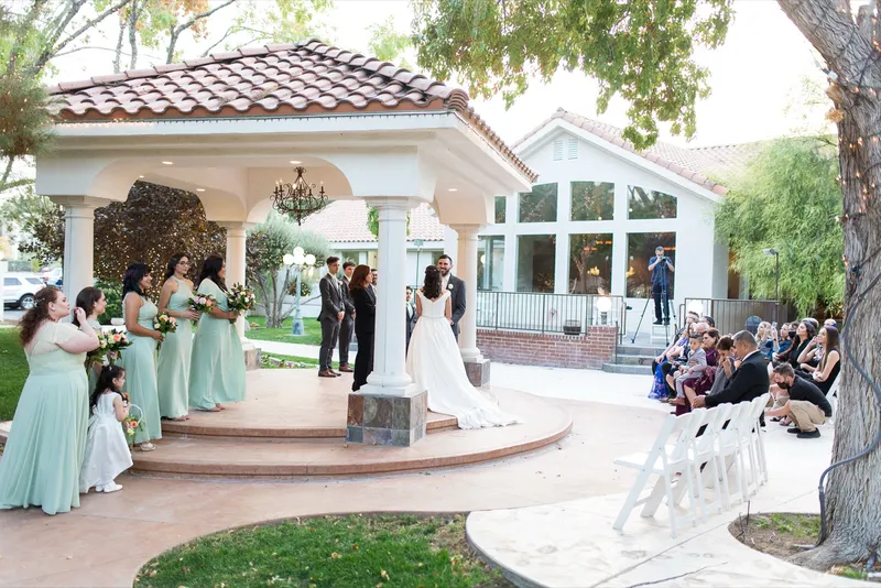 Ceremony on the raised pavilion with bridesmaids in mint standing to one side and guests seated on the patio