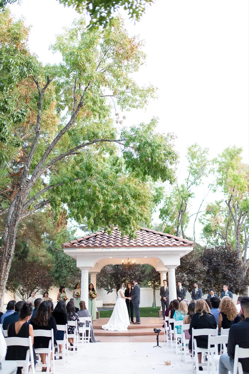 Ceremony seen from the back of the aisle, the pavilion lit ahead and every chair full