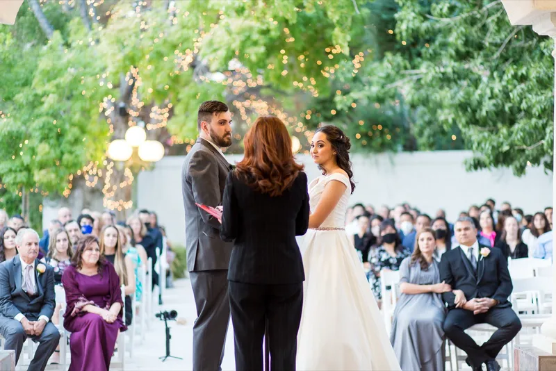 Couple facing the officiant during their vows while the seated guests watch from both sides of the aisle