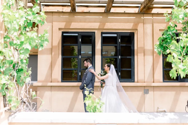 Bride and groom seeing each other for the first time beside the tall windows of the walkway, vines climbing the column next to them