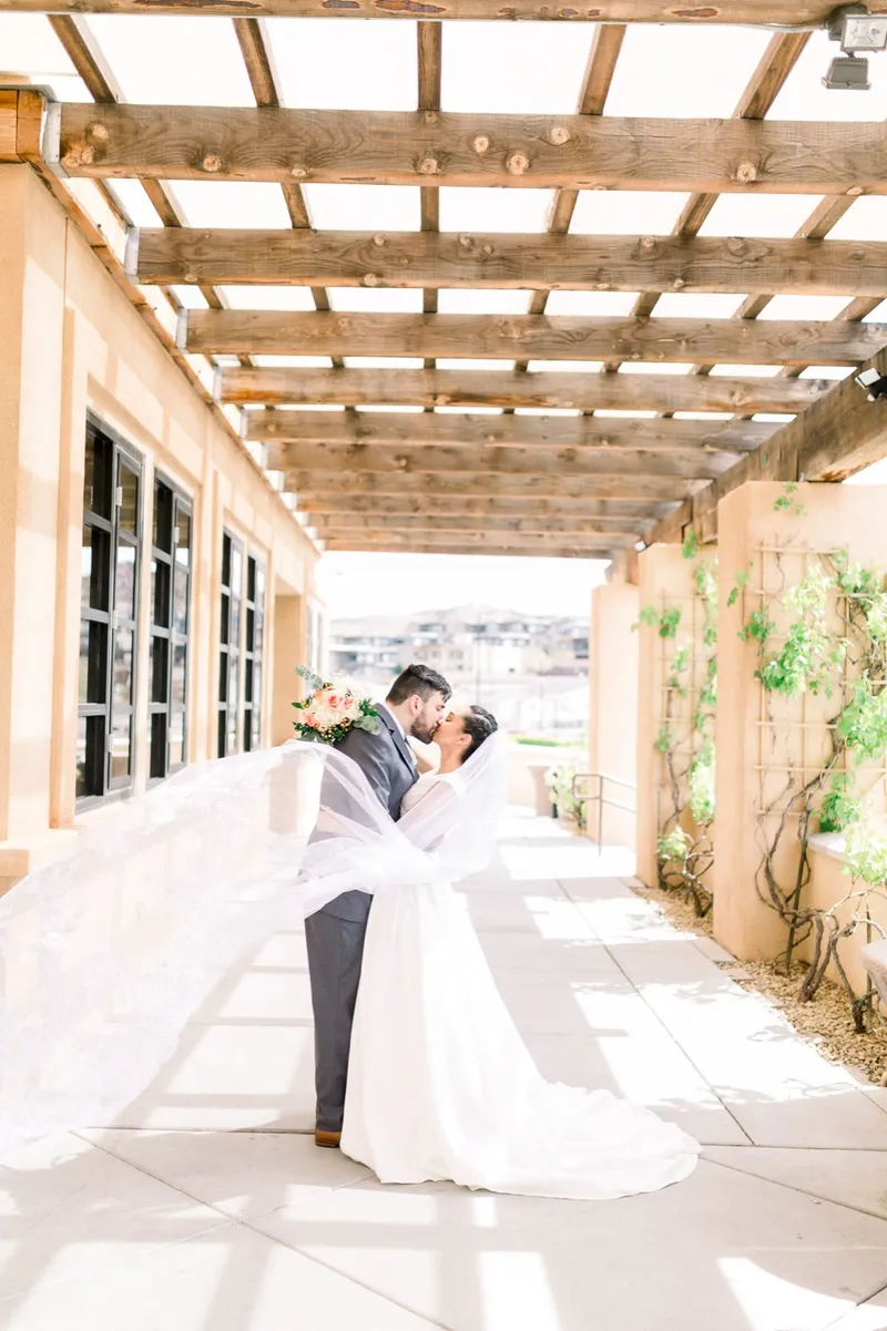 Couple kissing under the wood beams with her long veil blown out behind her