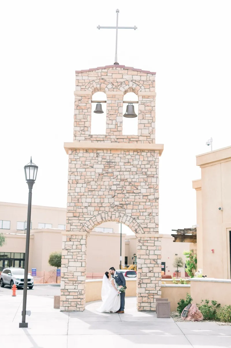 Couple kissing inside the stone arch underneath the bell tower