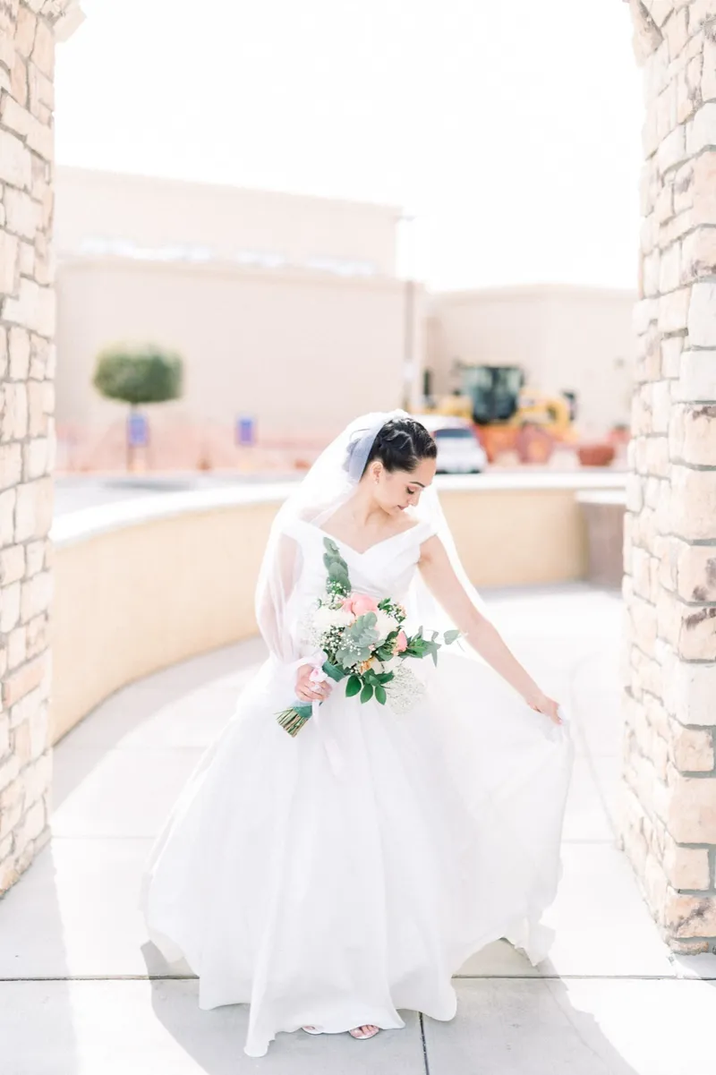 Bride walking along the church walkway holding her bouquet in one hand and her skirt in the other