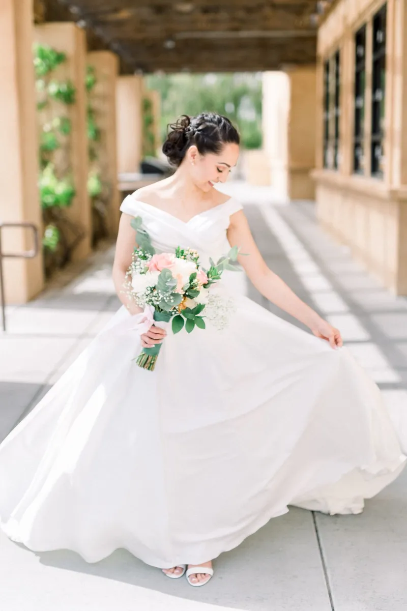 Bride swinging the full skirt of her gown out wide under the wood beams of the walkway