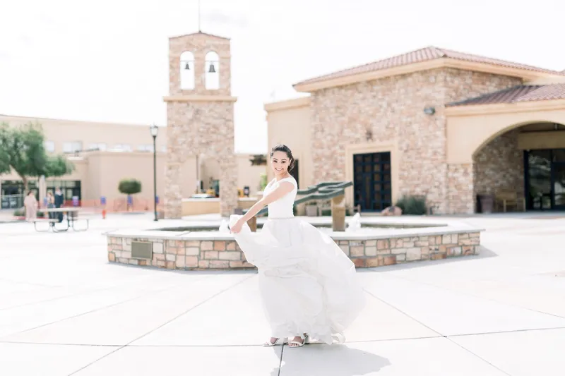 Bride turning in the plaza with her skirt flying out, the bell tower and the church roofline behind her