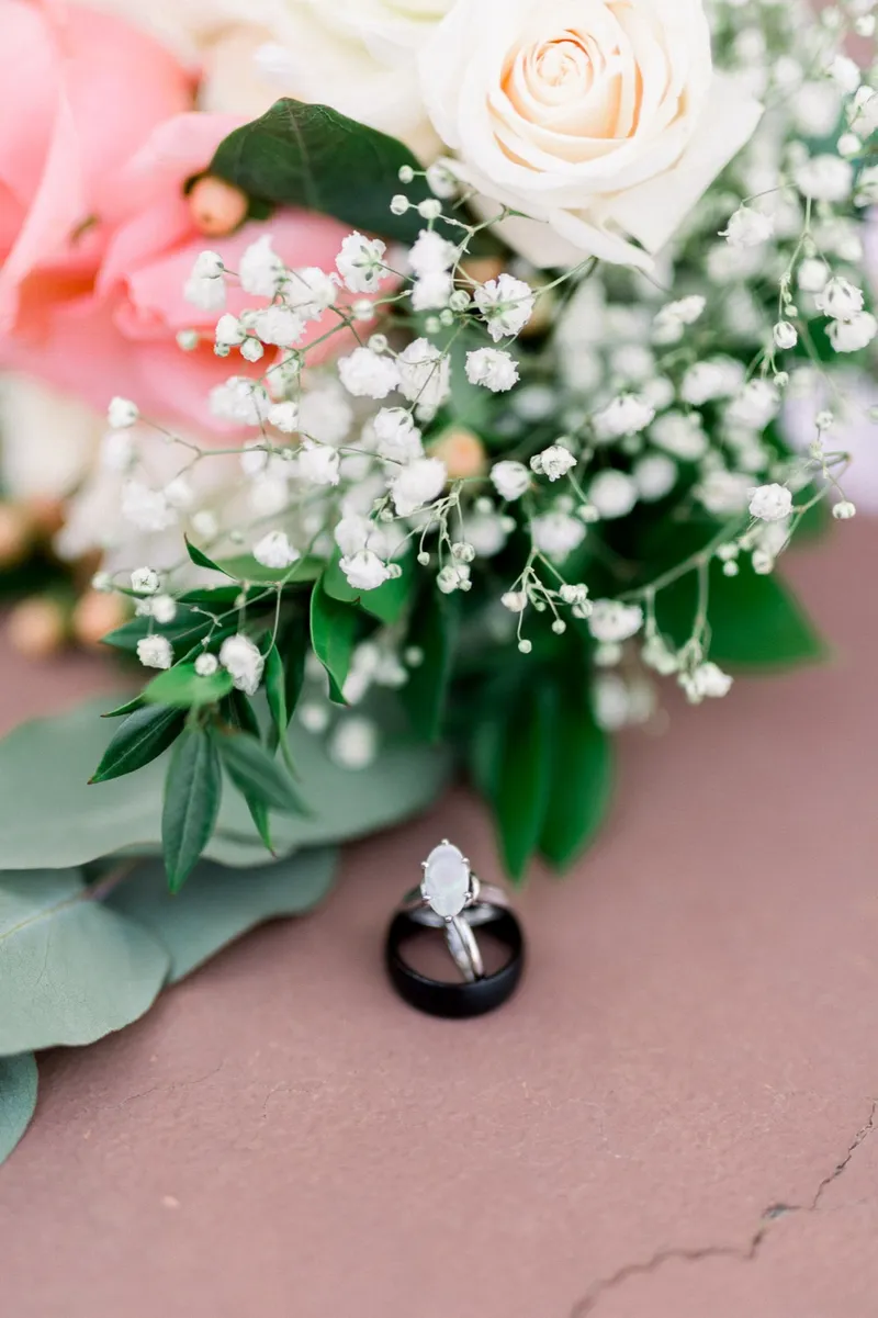 A wedding ring resting on the blush ribbon of the bouquet