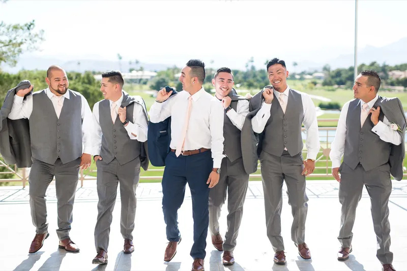 Groomsmen in grey vests walking together with the fairway and the mountains behind them