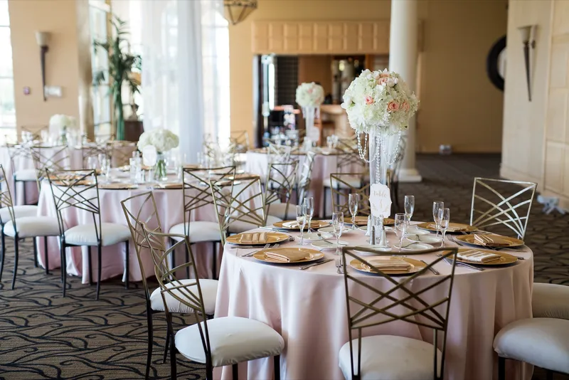 Round tables in blush linen with gold chargers and tall crystal centerpieces of white and blush roses