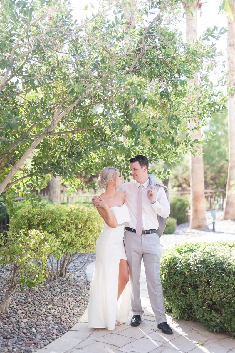 Couple holding each other on a garden path between the shrubs just after the first look