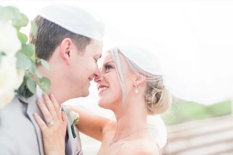 Close portrait of the couple under the veil with their foreheads pressed together