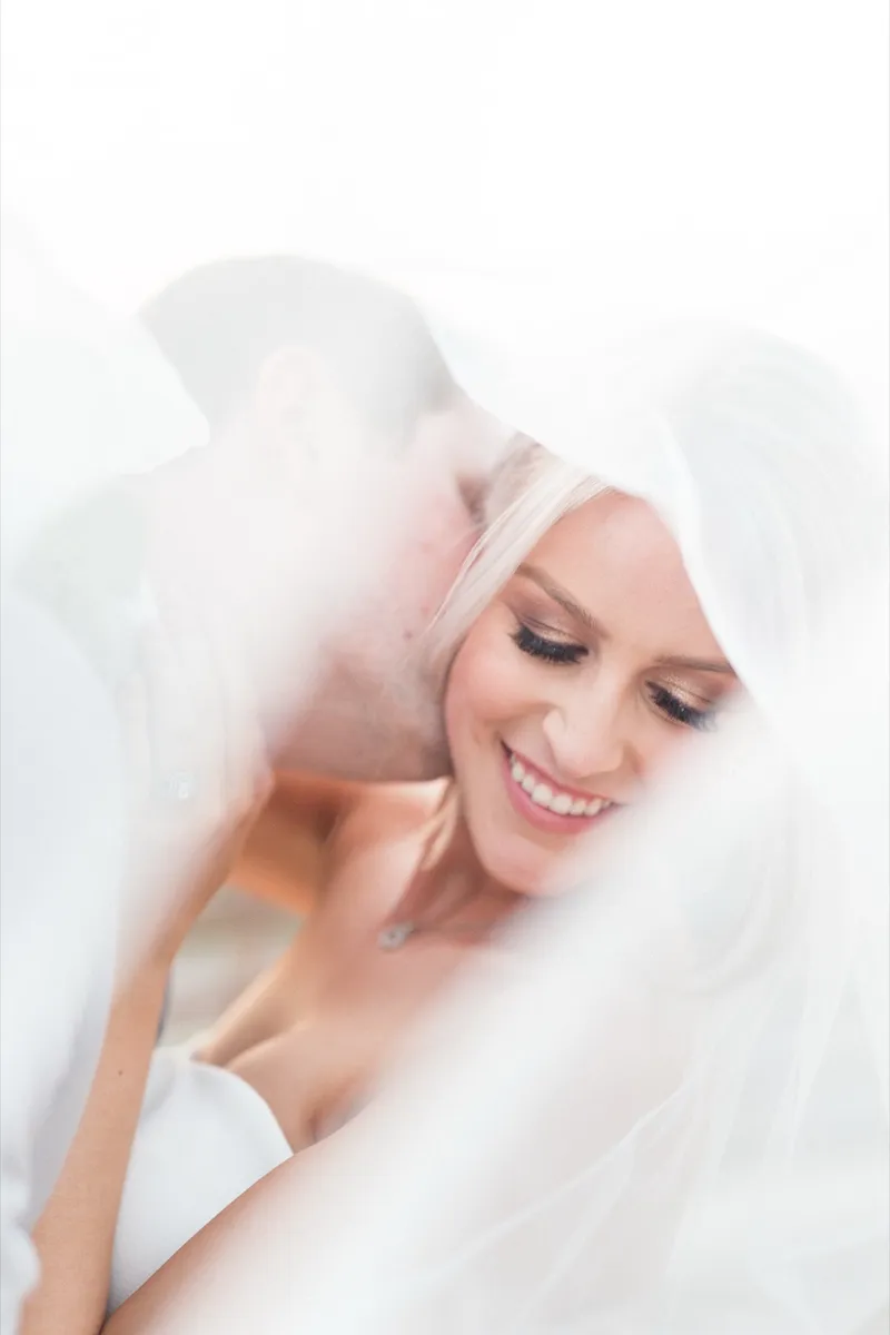 Soft close portrait of the bride smiling with her eyes down beneath her veil