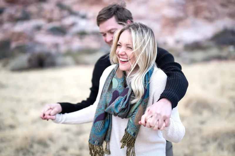 A couple laughing together at Red Rock Canyon right after a surprise proposal