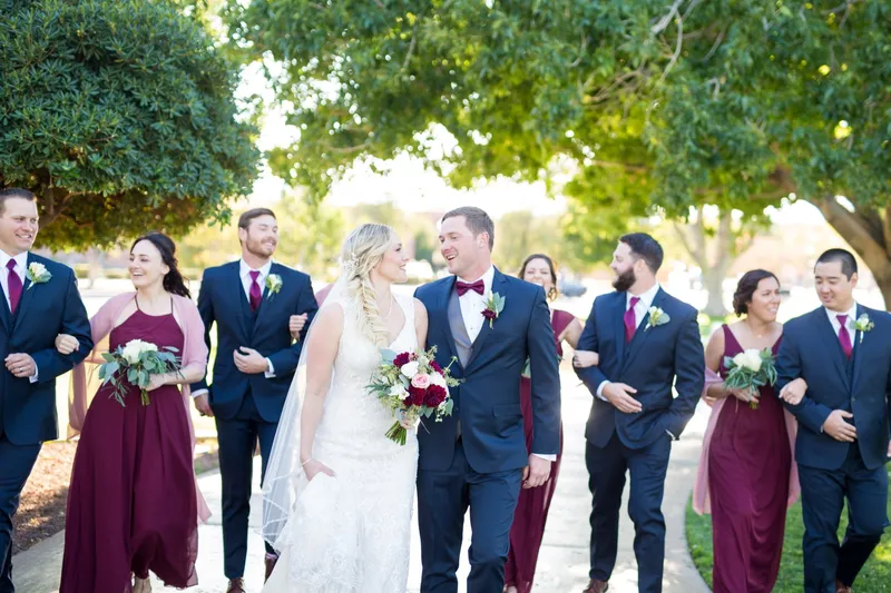 The couple stopping to kiss in the middle of the wedding party while everyone keeps walking around them
