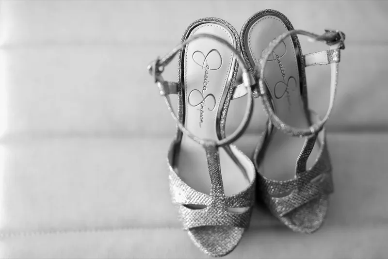 Black and white photo of the bride's glitter heels resting on the hotel bed