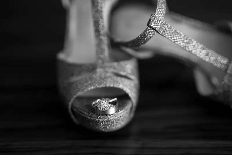 Black and white close view of the rings balanced inside the open toe of a glitter heel