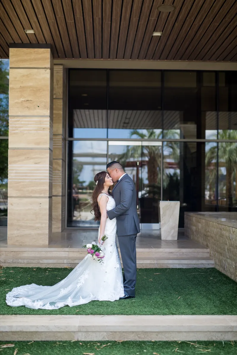 Bride and groom kissing on a strip of grass in front of the resort's tall glass entrance doors