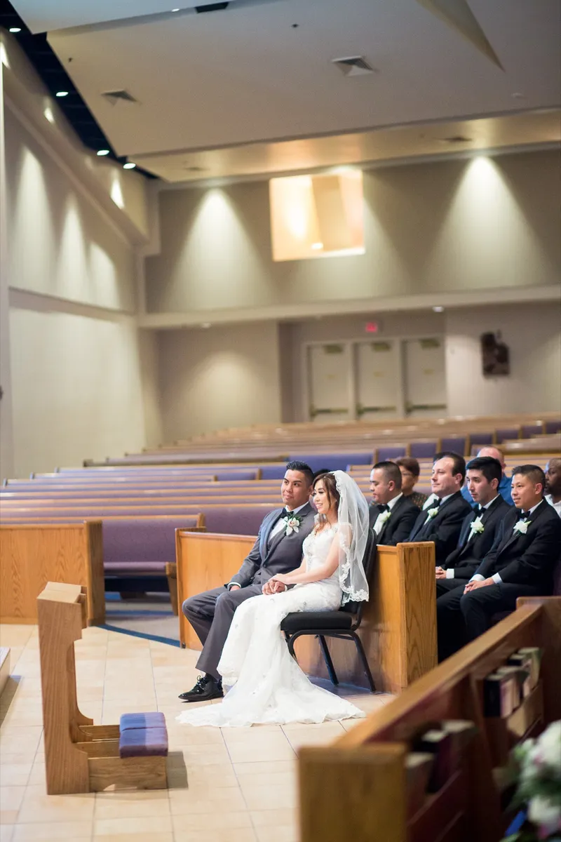 Bride and groom seated at the front of the church with their wedding party in the pews behind them