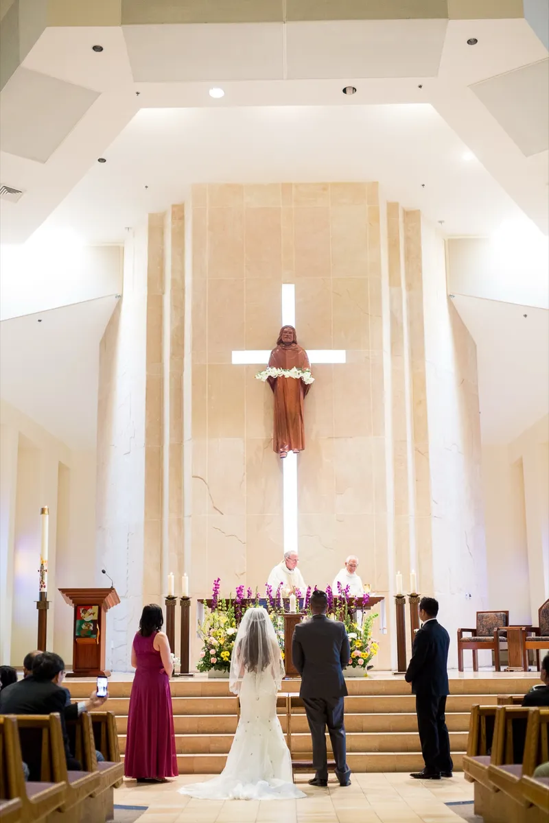 The ceremony seen from the back of the aisle, the couple standing at the altar steps with their wedding party beside them