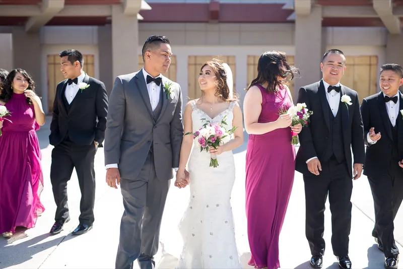 Bride and groom walking out under the covered entry of the church with their wedding party close around them