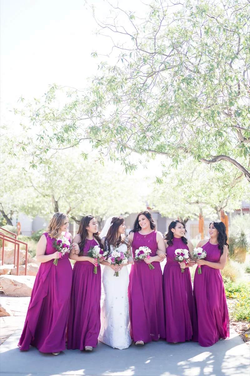 Bride and her bridesmaids laughing together in the shade of the courtyard trees