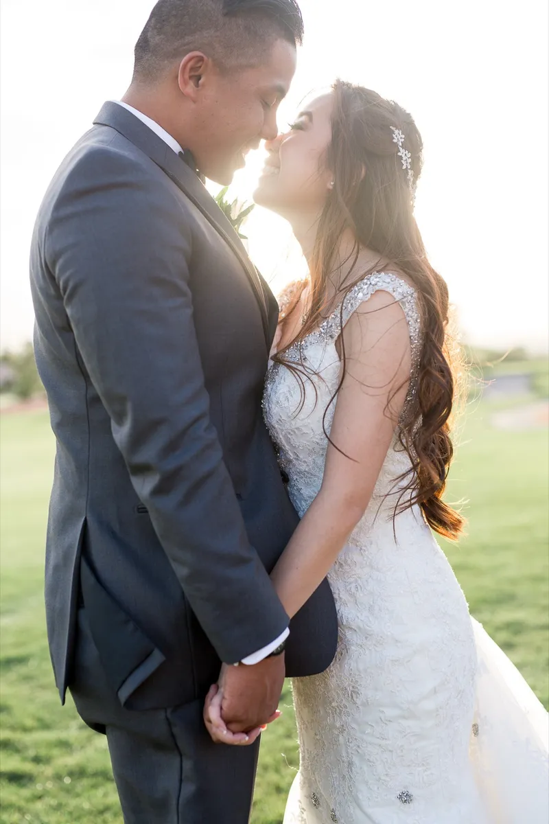 Couple standing close together on the grass about to kiss, the low sun burning out the sky behind their heads