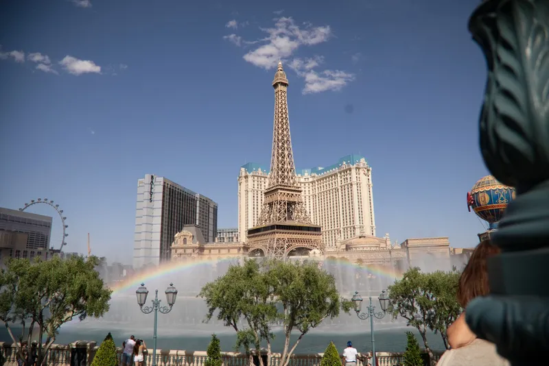 Rainbow arcing through the spray of the Bellagio fountains with the Eiffel Tower replica behind it