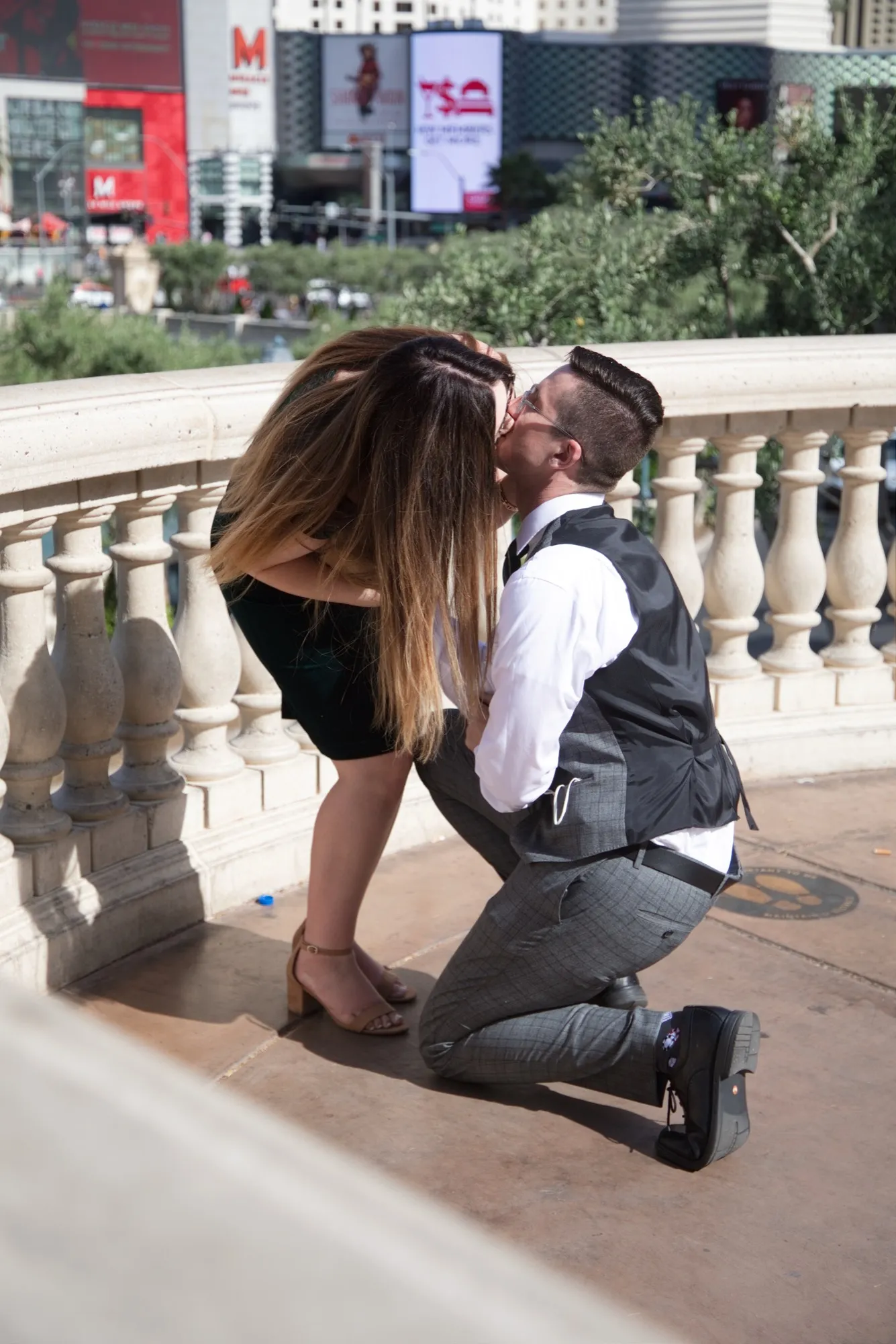 A newly engaged couple kissing on a Bellagio balcony high above the Las Vegas Strip