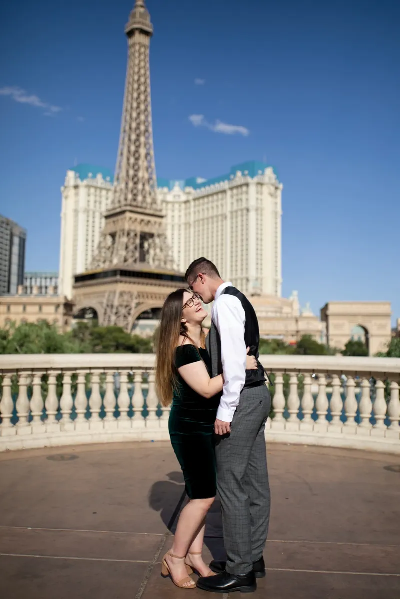 She leans into him at the curved railing while the Paris Las Vegas tower rises behind their shoulders