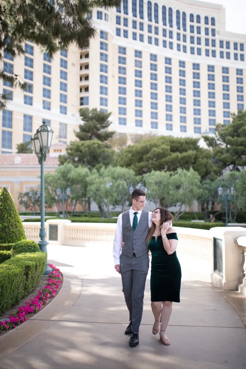 The two of them walking toward the camera on the garden path below the Bellagio's front tower