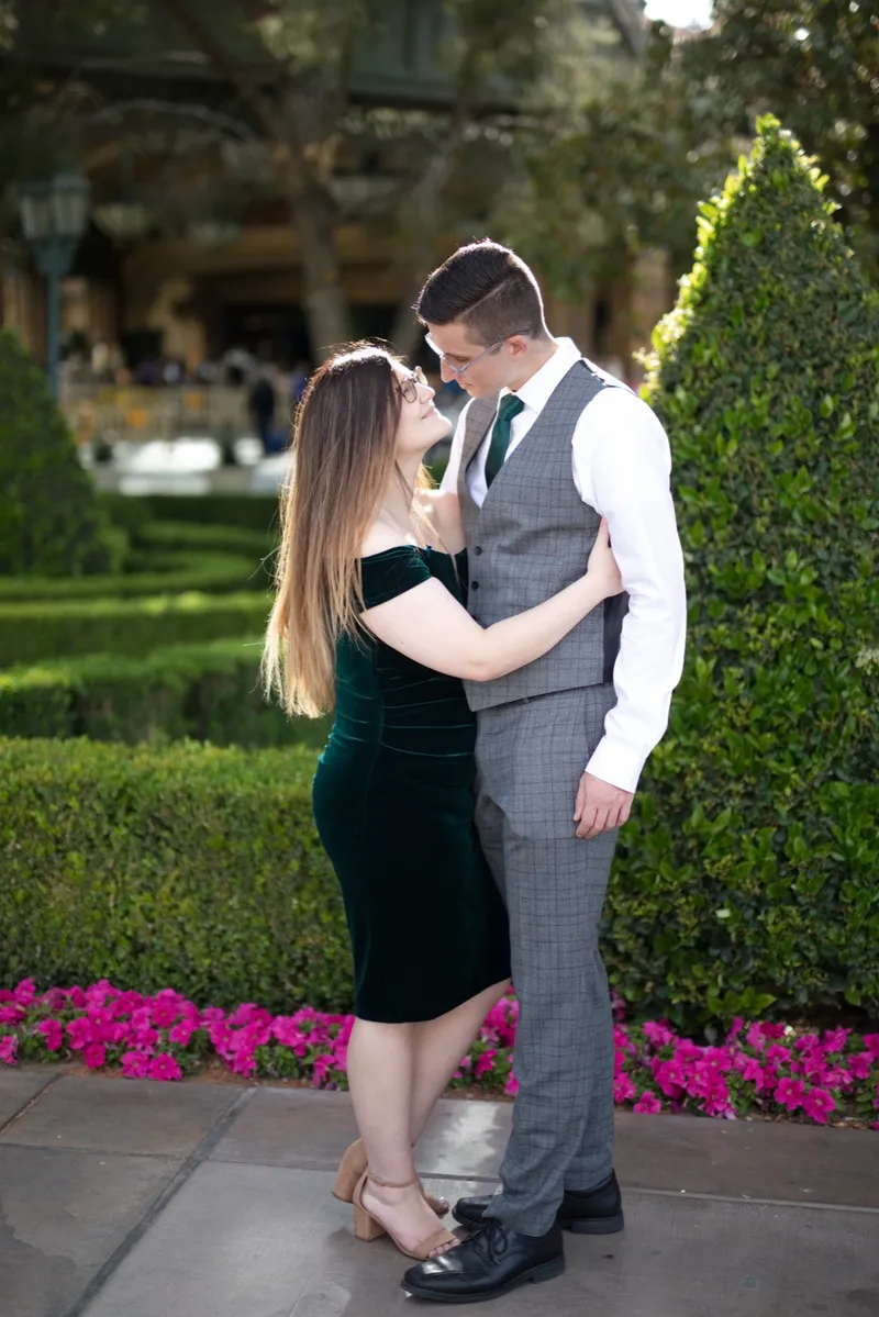 He holds her close on a garden path lined with bright pink flowers