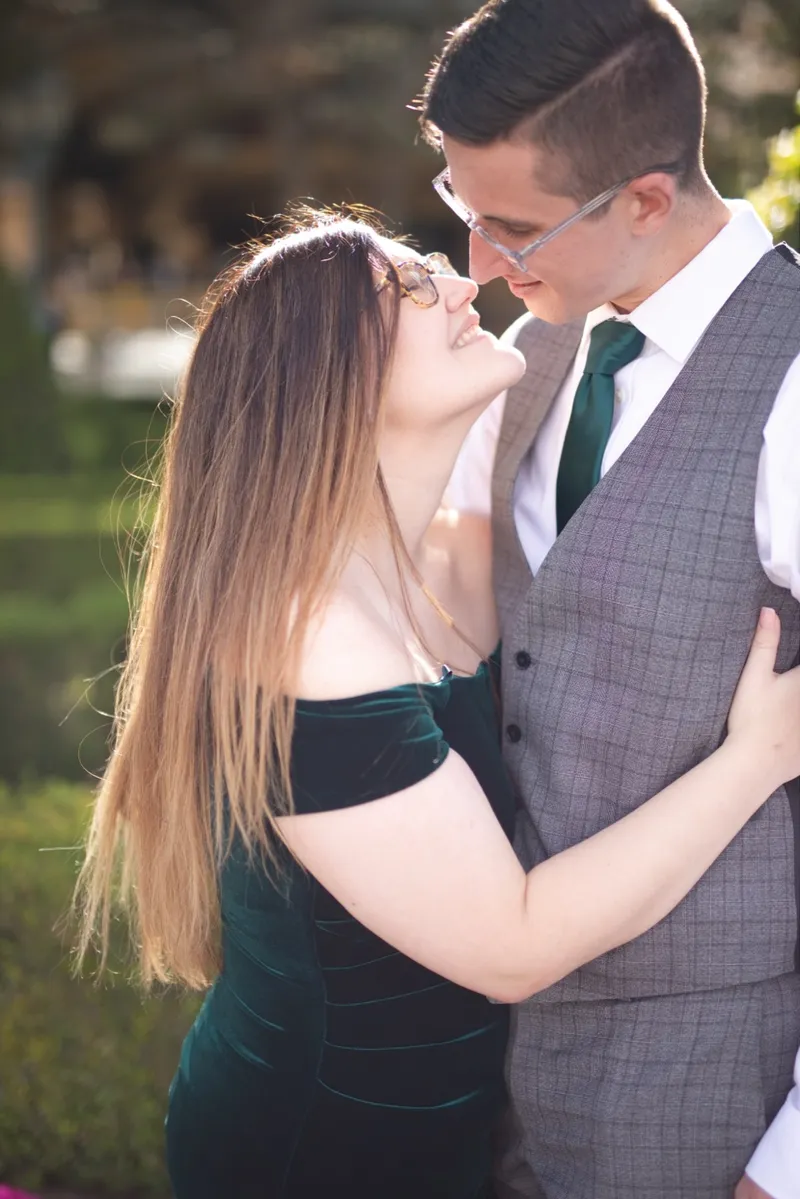 She laughs up at him with both arms wrapped around his waist in the afternoon sun