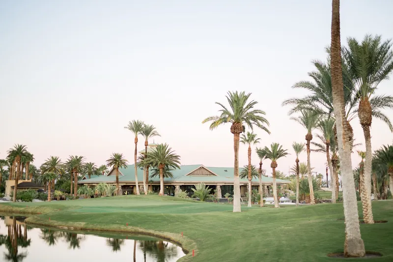 The clubhouse with its green roof seen across the lake and fairway at dusk