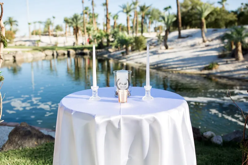 Unity candle table dressed in white linen set at the front of the aisle with the lake behind it