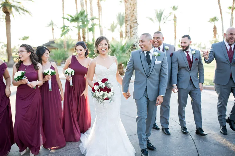 A bride and groom celebrating with their burgundy and gray wedding party under palm trees at a Las Vegas venue