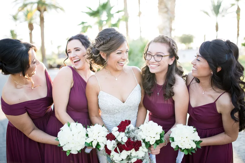 Bride in the middle of a huddle of bridesmaids, everyone laughing at once