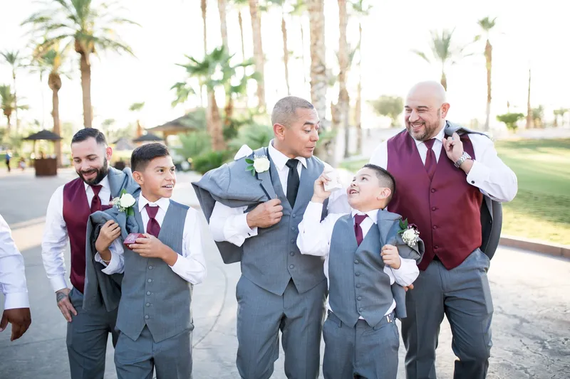 Groom messing around with his groomsmen and two young ring bearers on the path