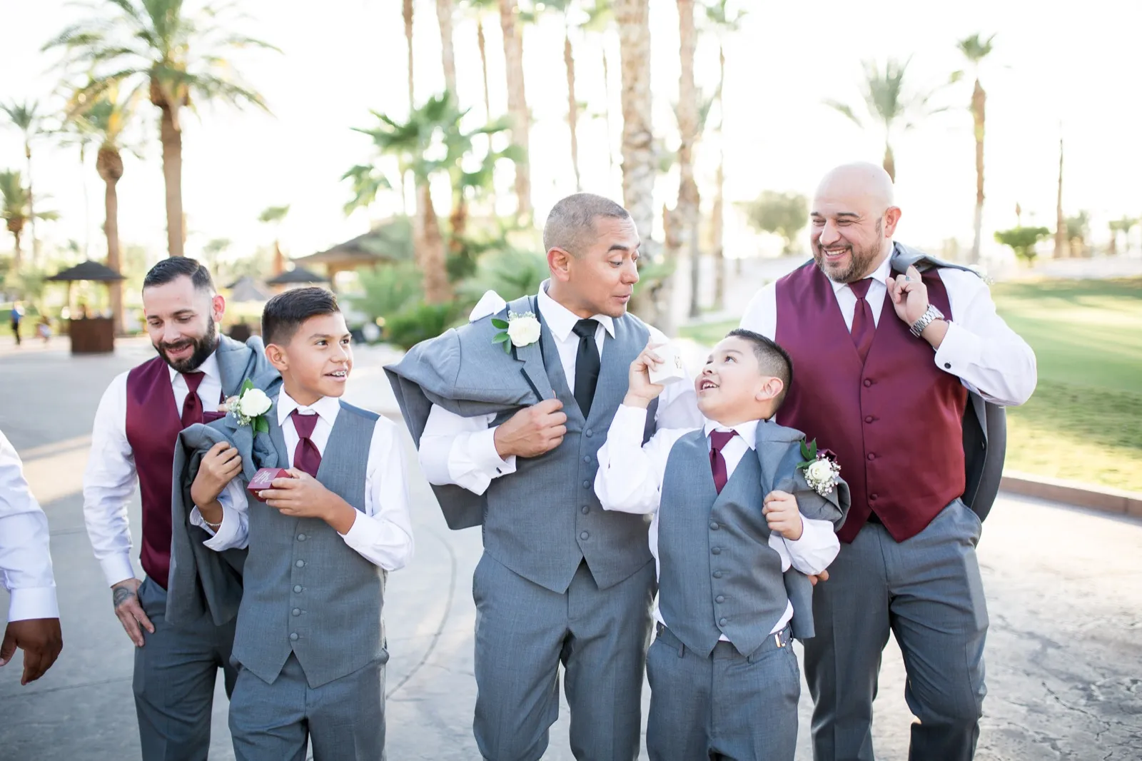 Groom on the clubhouse drive with his groomsmen and two young ring bearers, one holding up a ring box