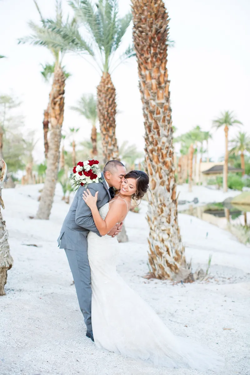 Bride and groom kissing in a dip under the palms in the last of the light