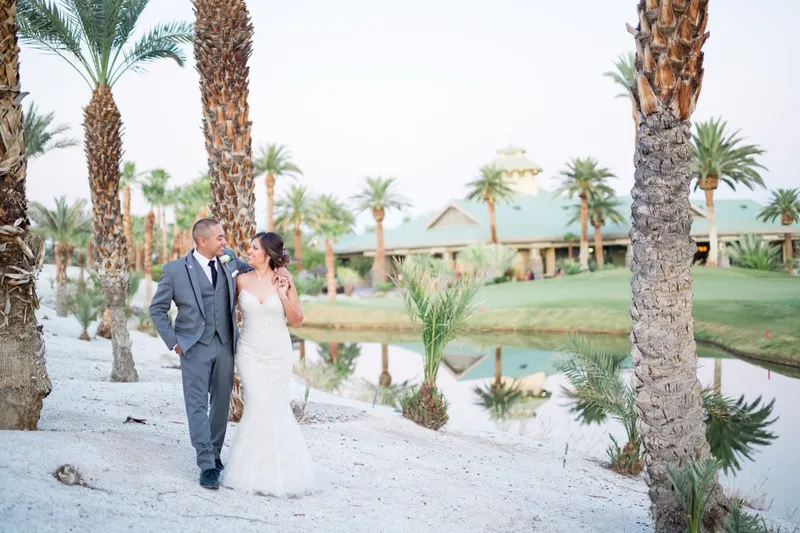 Bride and groom standing together on the white sand with the lake and clubhouse across the water