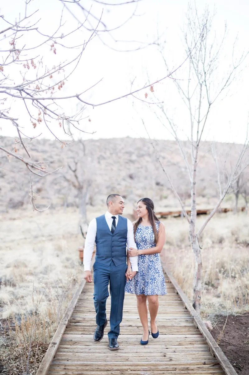 Couple walking toward the camera along a raised wooden boardwalk through the desert