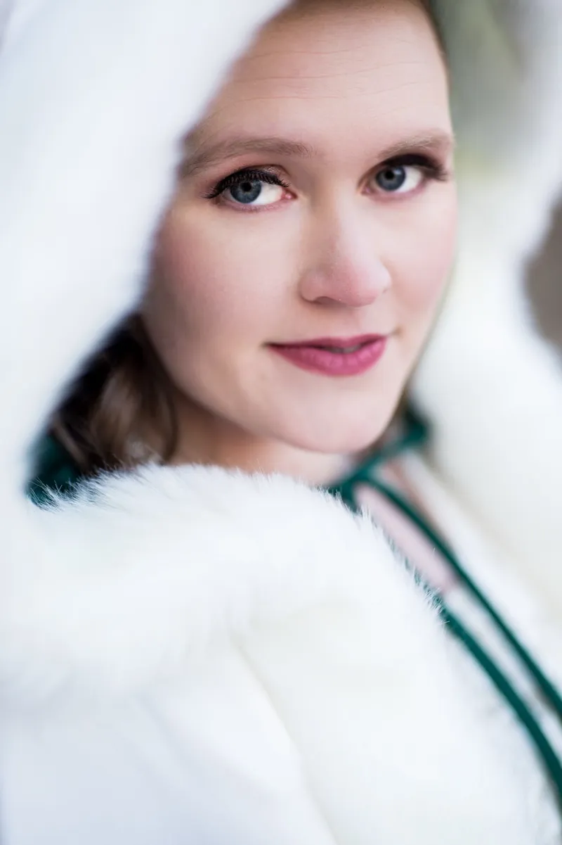 Close portrait of a bride in a white fur trimmed hood looking at the camera