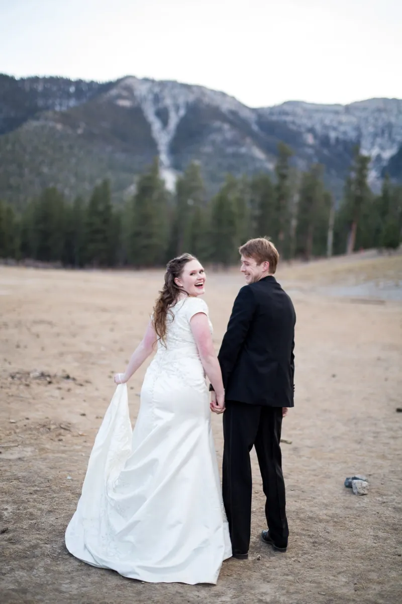 Bride laughing over her shoulder at her groom in the open meadow