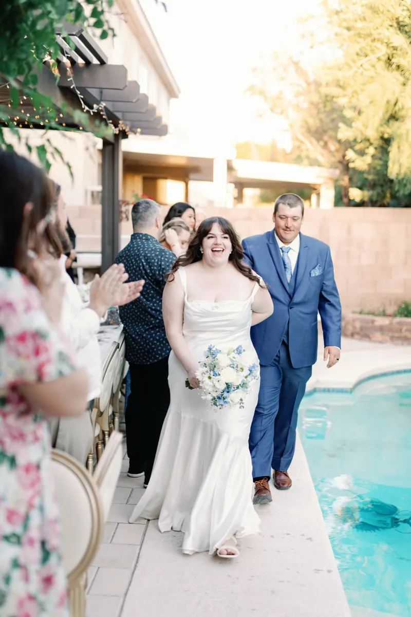 Bride and groom walking the pool deck into the reception as the seated guests clap them in