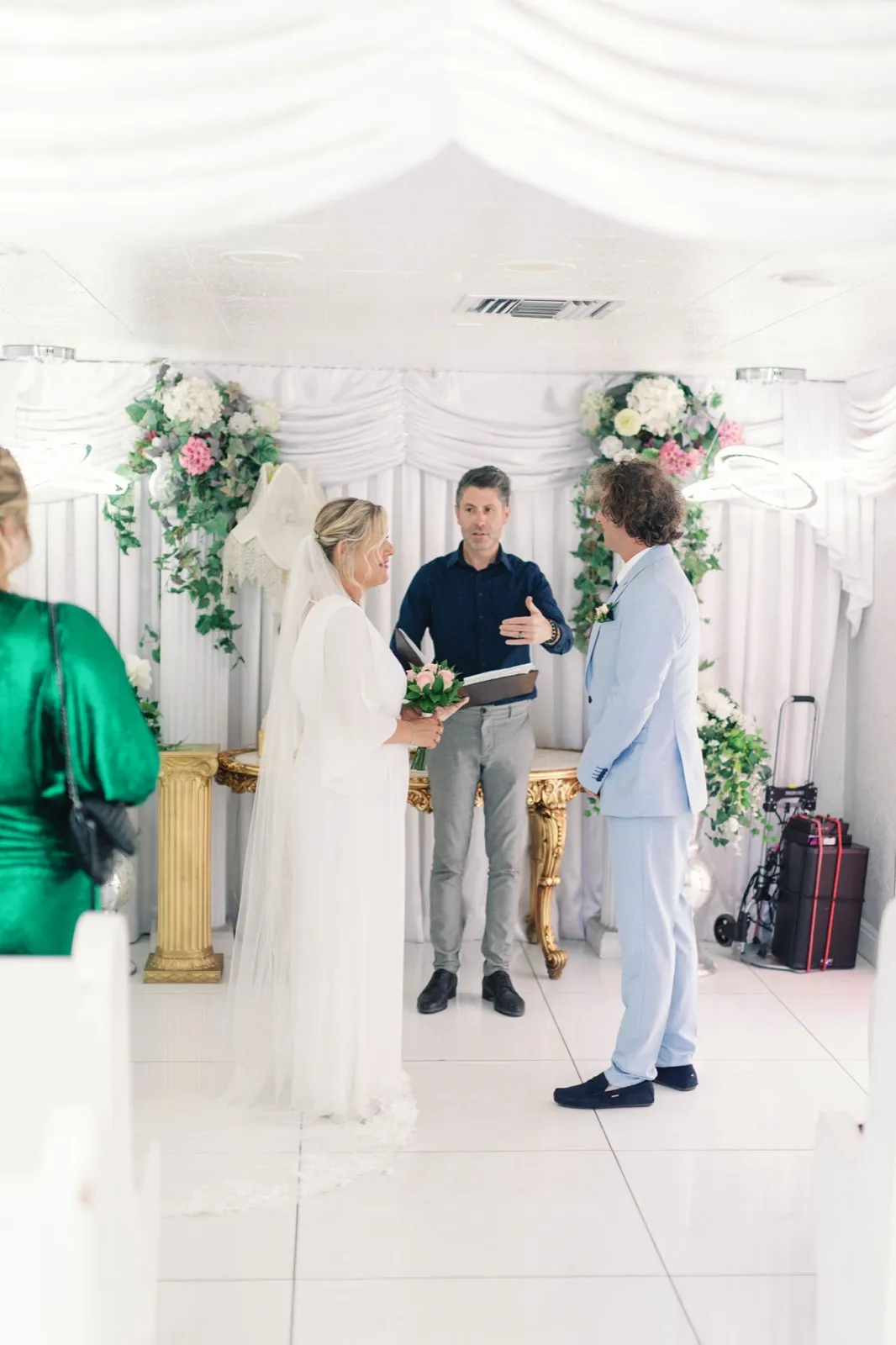 Bride and groom facing their officiant between white pews in a small Las Vegas wedding chapel