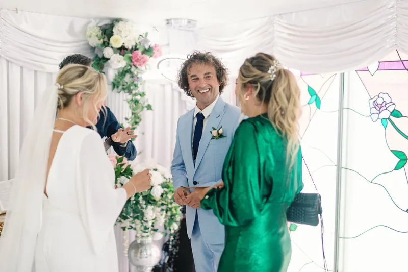 Couple at the altar with a guest in emerald green watching from the front row