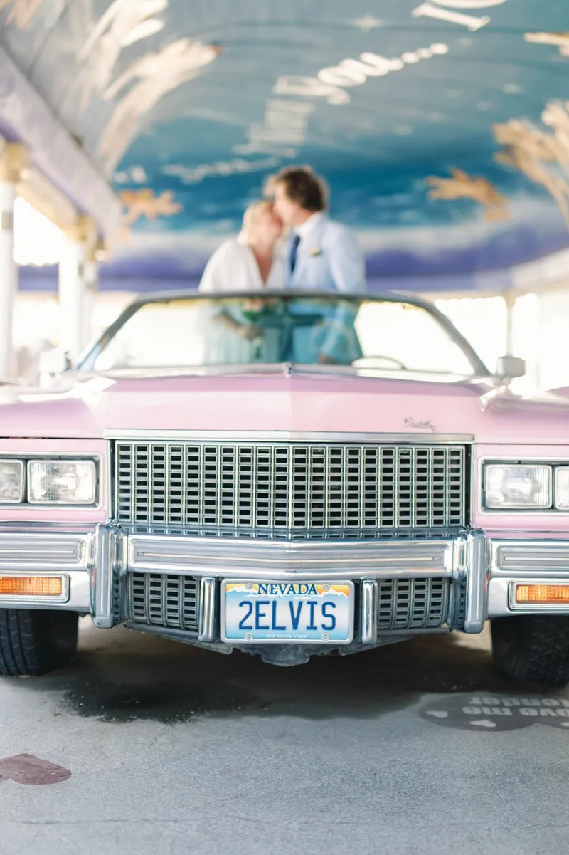 Bride laughing beside the pink Cadillac as her groom leans on the door