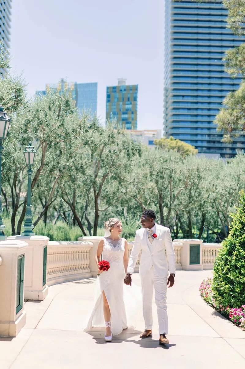 Bride and groom walking the path together with the blue glass towers of the Strip behind them