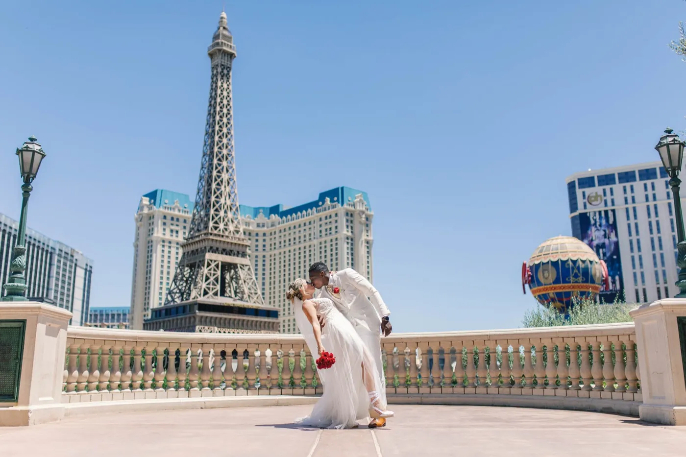 Groom dipping his bride for a kiss on the Bellagio overlook with the Paris Las Vegas Eiffel Tower behind them